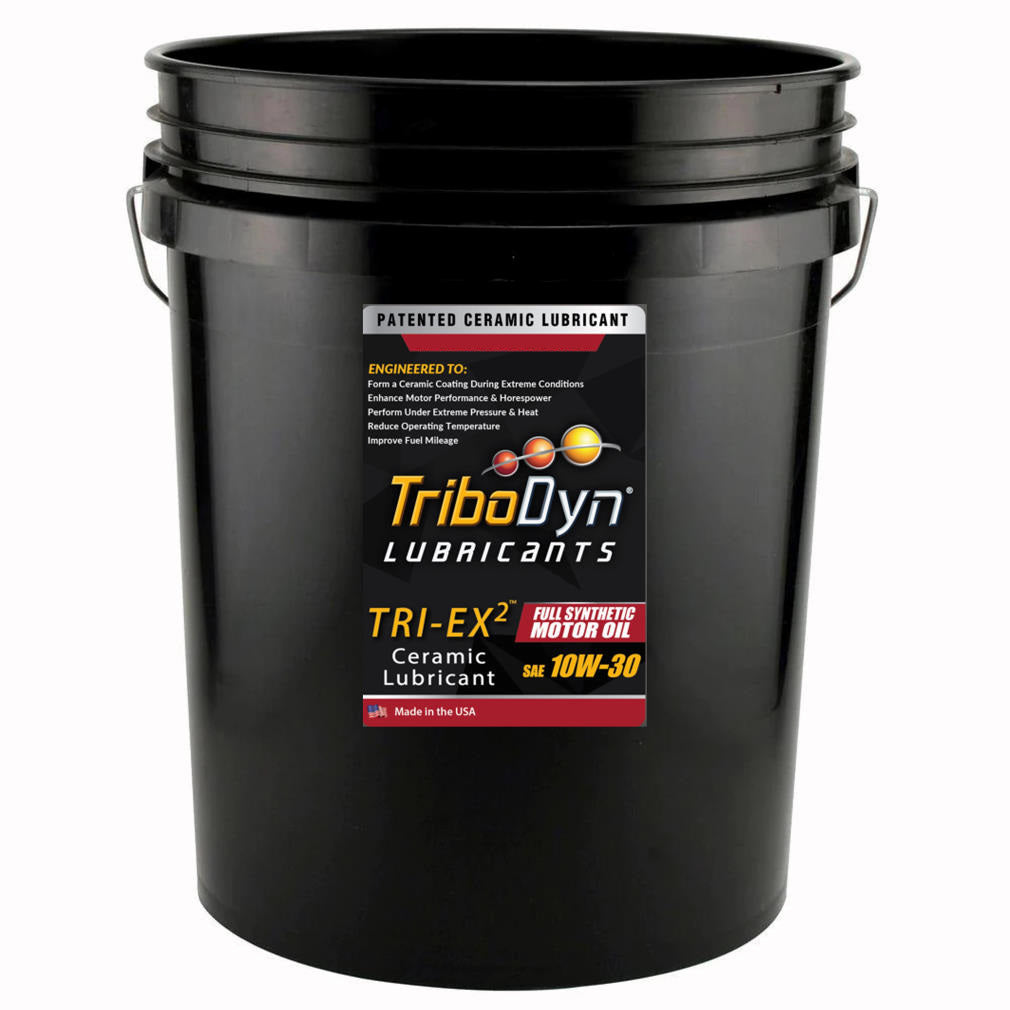 A black five gallon bucket with a label for TriboDyn TRI-EX 2 SAE Full Synthetic 10w30 Oil with Ceramic Coating