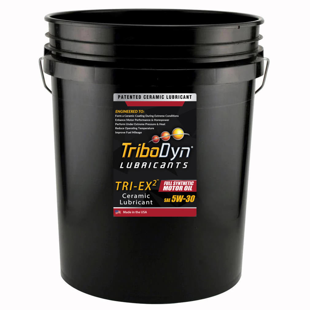 A black five gallon bucket with a label for TriboDyn TRI-EX2 5W-30 Full Synthetic Motor Oil with ceramic coating